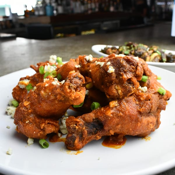 Lilo's Streetfood & OKA Sushi's buffalo wings, topped with blue cheese crumbles and green onions.