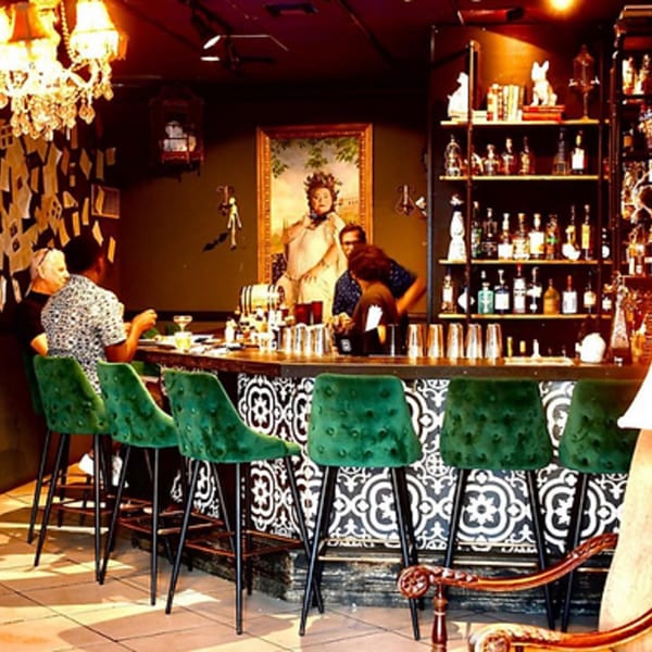 Lilo's Streetfood & OKA Sushi bar with patrons, green velvet stools, and a large portrait.