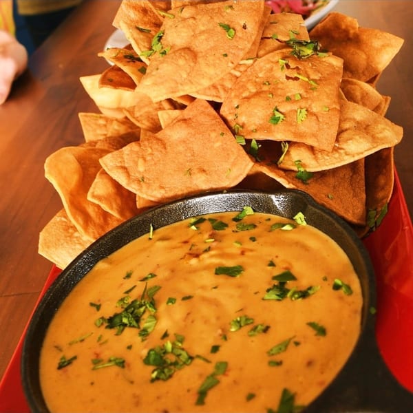 Crispy tortilla chips with cilantro, served with a cast iron skillet of creamy queso dip.