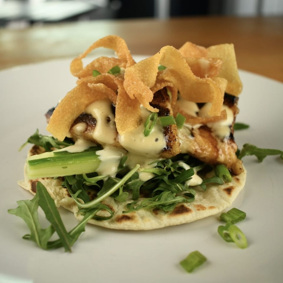 Lilo's Streetfood chicken taco with crispy wontons, creamy sauce, arugula, and green onions.