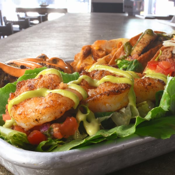 Lilo's Streetfood & OKA Sushi's shrimp tacos with avocado crema, lettuce, and diced tomatoes.